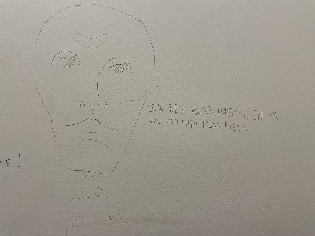 Thin line drawing of a face with writing next to it.